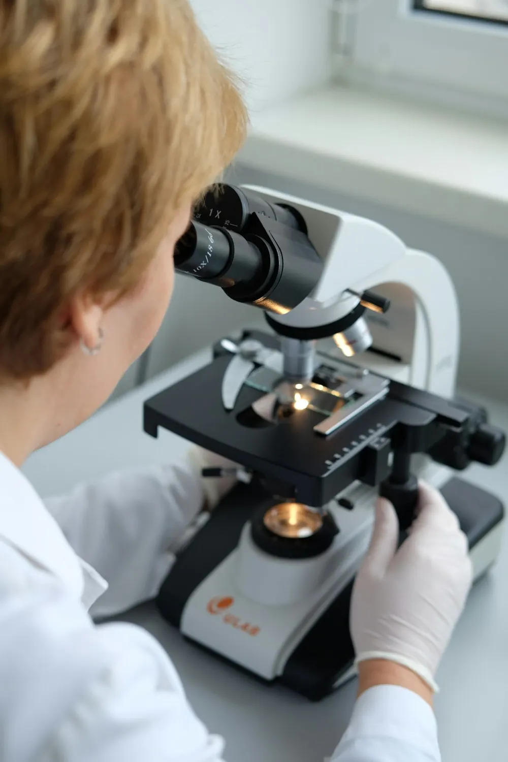 Profissional de laboratório analisando lâmina no microscópio
