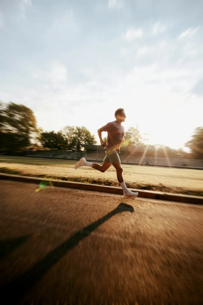 Pessoa correndo em pista de atletismo ao entardecer